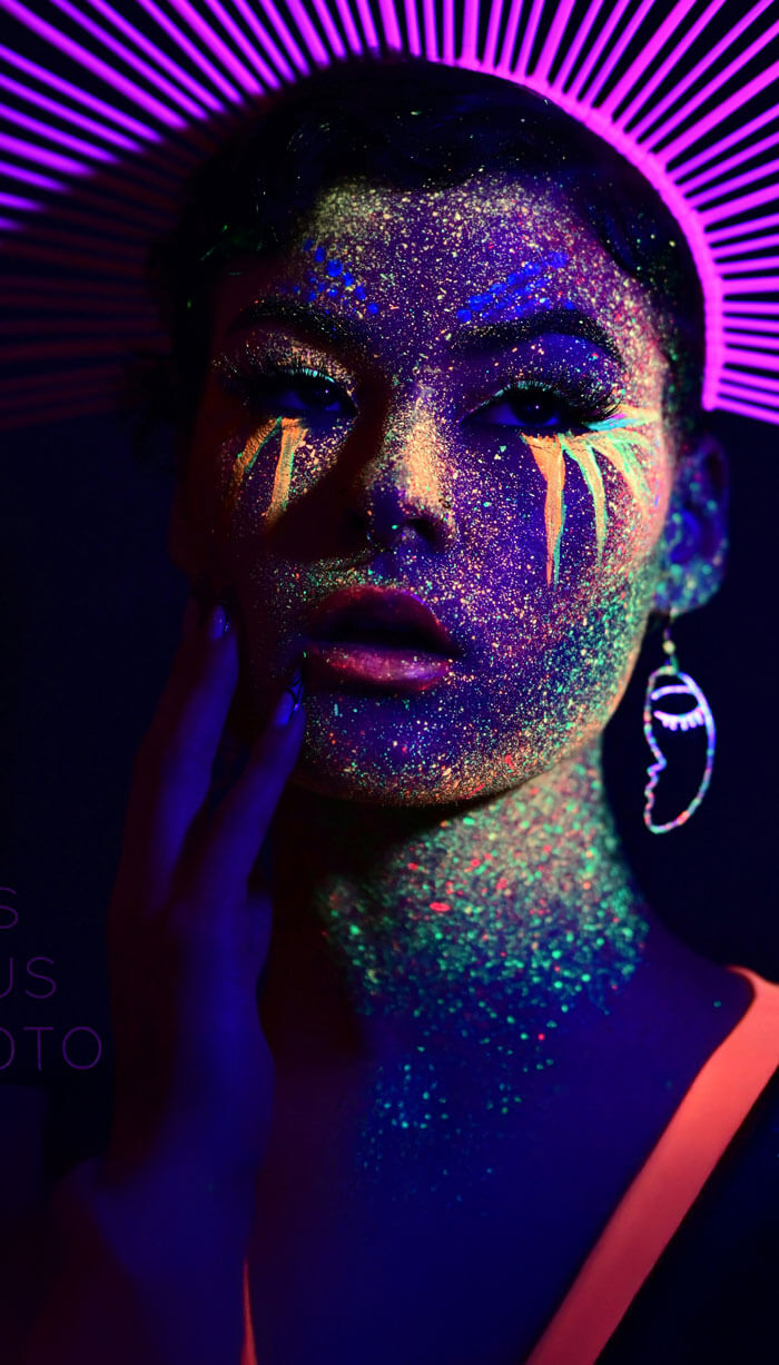 Woman with luminescent glitter on her face and glowing earrings
